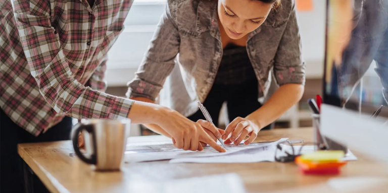 Menschen beugen sich über einen Bauplan